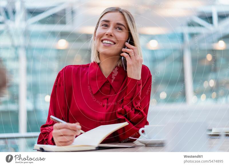 Lächelnde junge Geschäftsfrau mit Notebook am Telefon Job Berufe Berufstätigkeit Beschäftigung Jobs geschäftlich Geschäftsleben Geschäftswelt Geschäftsperson