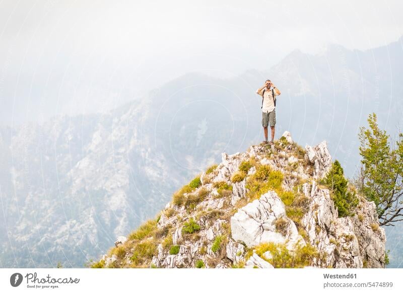 Italien, Massa, Mann stehend auf einem Gipfel in den Alpi Apuane Bergen Männer männlich steht Berggipfel Gebirge Berglandschaft Gebirgslandschaft Gebirgskette