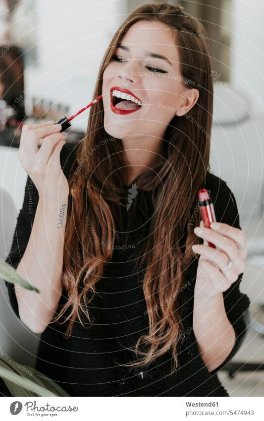 Porträt einer glücklichen jungen Frau, die Lippenstift aufträgt weiblich Frauen anwenden auftragen Lippenstifte Glück glücklich sein glücklichsein Portrait