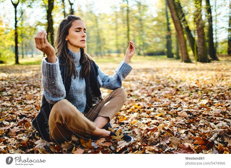 Junge Frau meditiert im Herbstwald sitzend sitzt geniessen Genuss frei Muße konzentrieren konzentriert meditieren alleine einzeln Travel Ausfluege Ausflüge