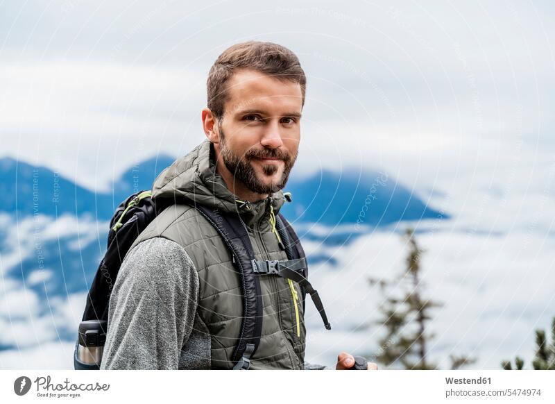 Porträt eines selbstbewussten jungen Mannes auf einer Wanderung in den Bergen, Herzogstand, Bayern, Deutschland Touristen Rucksäcke gehend geht allein zufrieden
