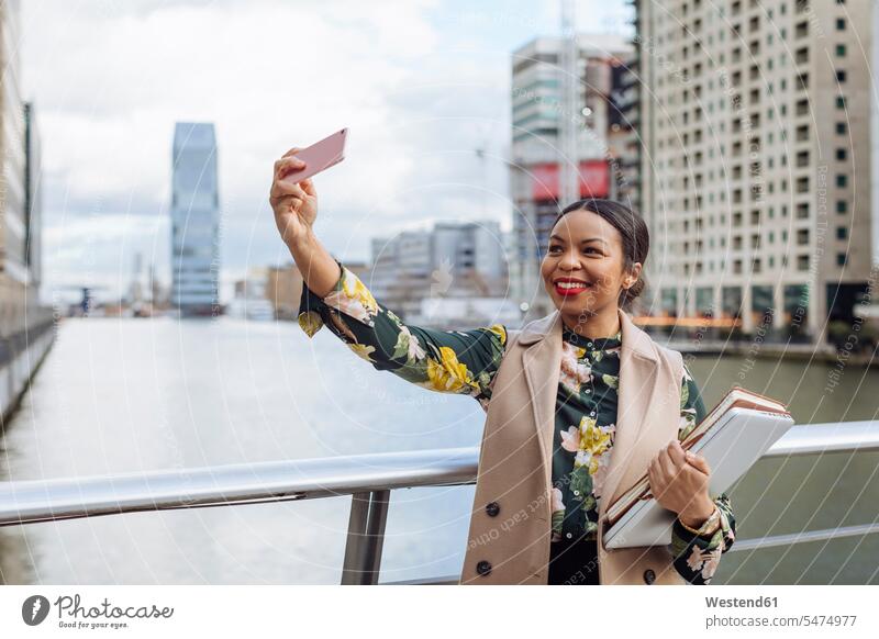 UK, London, Porträt einer modischen Geschäftsfrau, die ein Selfie mit ihrem Handy macht Portrait Porträts Portraits Smartphone iPhone Smartphones