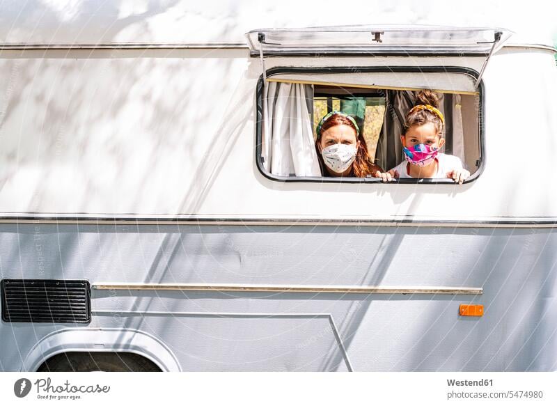 Mutter und Tochter tragen Masken und schauen durch das Fenster eines Wohnmobils Farbaufnahme Farbe Farbfoto Farbphoto Spanien Freizeitbeschäftigung Muße Zeit