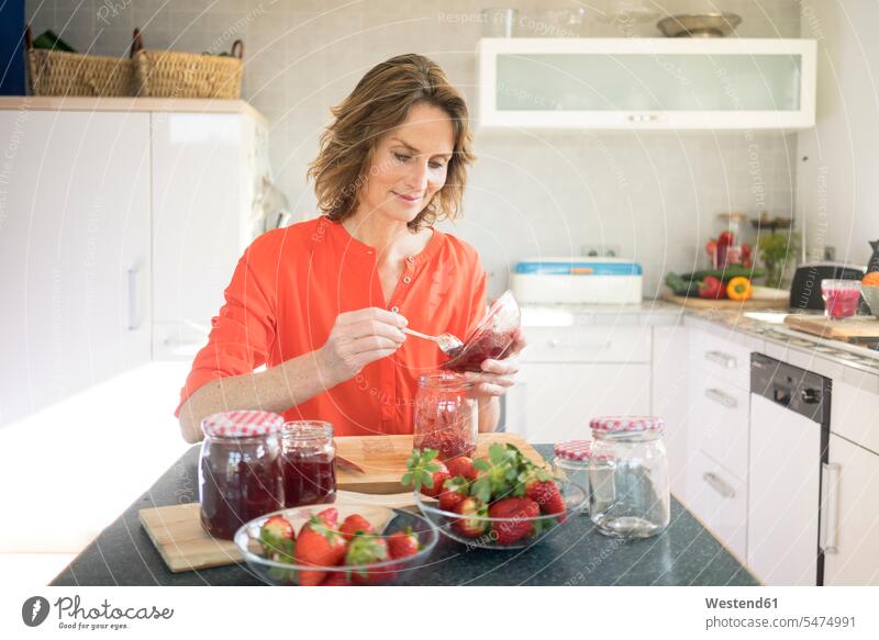 Frau macht zu Hause in der Küche Erdbeermarmelade Marmelade weiblich Frauen Zuhause daheim Brotaufstrich Aufstrich Brotaufstriche Essen Food Food and Drink