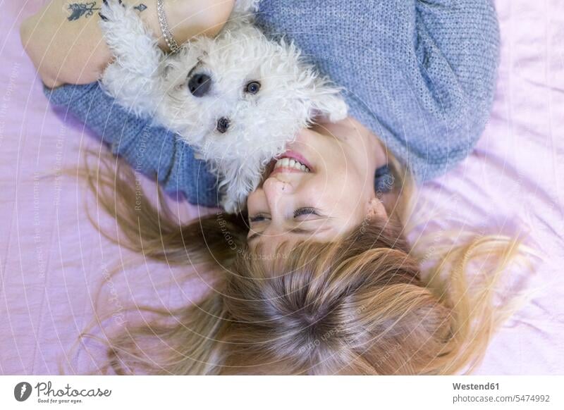 Glückliche Frau liegt mit ihrem Hund im Bett Hunde glücklich glücklich sein glücklichsein liegen liegend weiblich Frauen Betten Haustier Haustiere Tier Tierwelt