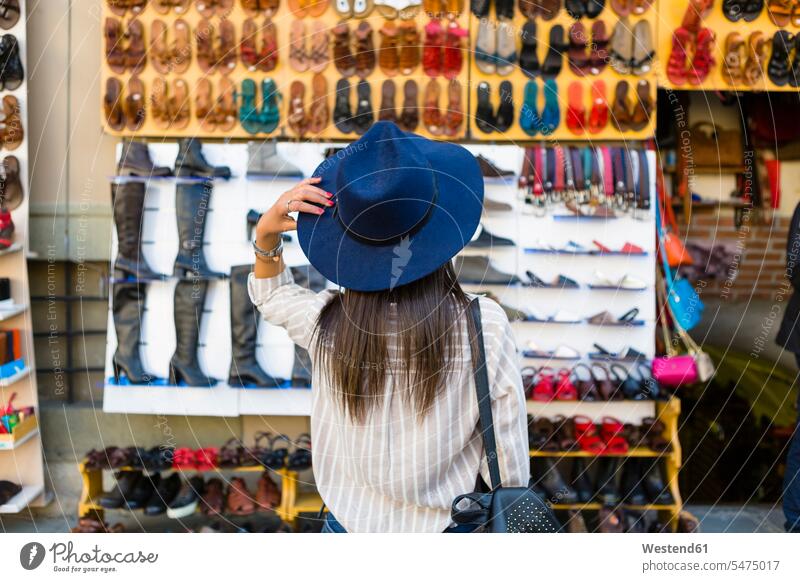 Italien, Florenz, Rückenansicht eines jungen Touristen, der das Angebot von Lederwaren auf der Straße beobachtet Angebote anbieten Rückansicht Rueckansicht