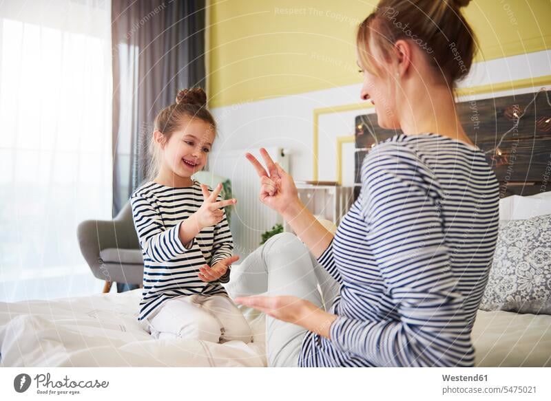 Mutter und Tochter haben Spaß zusammen, spielen, sitzen auf dem Bett Betten Mami Mutti Mütter Mama Mädchen weiblich Töchter Spass Späße spassig Spässe spaßig