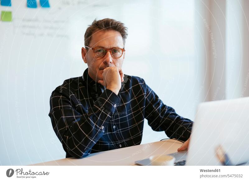 Porträt eines seriösen Geschäftsmannes mit Laptop am Schreibtisch im Büro Notebook Laptops Notebooks Office Büros ernst Ernst Ernsthaftigkeit ernsthaft Portrait