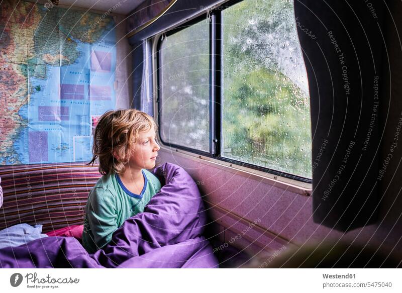 Junge im Pyjama schaut aus dem Fenster eines Wohnmobils Reisemobil Camper Wohnmobile Wohnwagen Campingbus Buben Knabe Jungen Knaben männlich Schlafanzuege