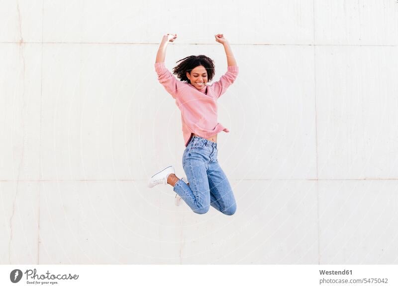 Glückliche junge Frau springt in die Luft gegen Licht Hintergrund springen hüpfen glücklich glücklich sein glücklichsein weiblich Frauen Luftsprung Luftsprünge
