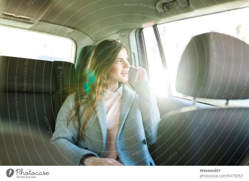 Junge Geschäftsfrau am Telefon, die auf dem Rücksitz eines Autos sitzt und aus dem Fenster schaut Geschäftsfrauen Businesswomen Businessfrauen Businesswoman