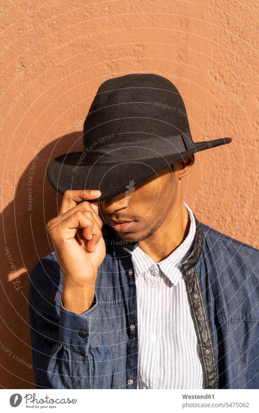 Stilvoller junger Mann mit Hut an der Wand Leute Menschen People Person Personen Afrikanisch Afrikanische Abstammung dunkelhäutig Farbige Farbiger Schwarze