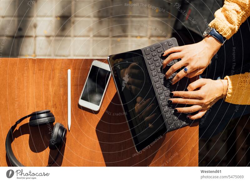 Hände einer Studentin, die auf einer digitalen Tablet-Tastatur tippt, während sie in einem Straßencafé in der Stadt sitzt Farbaufnahme Farbe Farbfoto Farbphoto