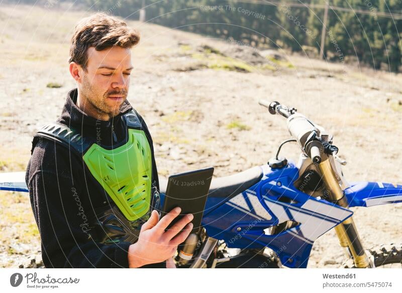 Porträt eines Motocross-Fahrers mit Blick auf ein Tablet Tablet Computer Tablet-PC Tablet PC iPad Tablet-Computer ansehen Rennstrecke Mann Männer männlich