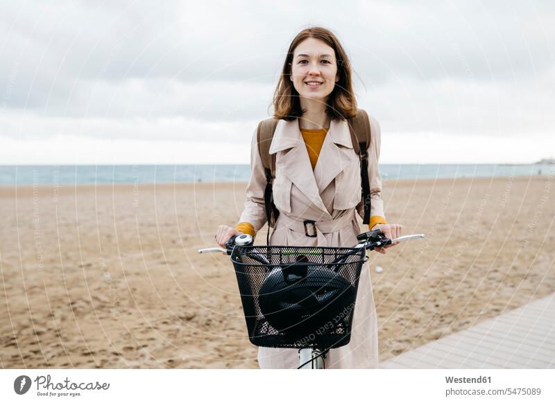 Porträt einer lächelnden Frau mit E-Bike am Strand Beach Straende Strände Beaches Fahrrad Bikes Fahrräder Räder Rad eBikes E-Bikes Elektrofahrrad Elektrorad