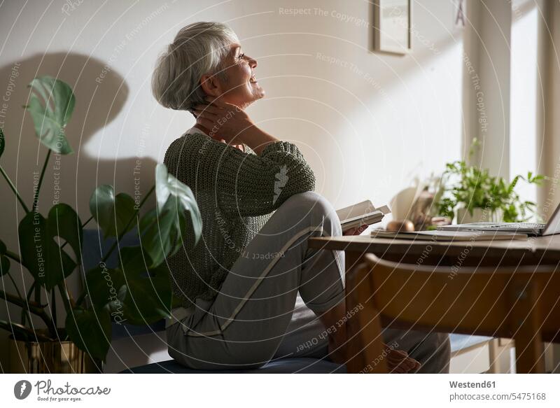 Zuversichtliche ältere Frau mit Notebook und Laptop entspannt zu Hause Leute Menschen People Person Personen Alleinstehende Alleinstehender Singles