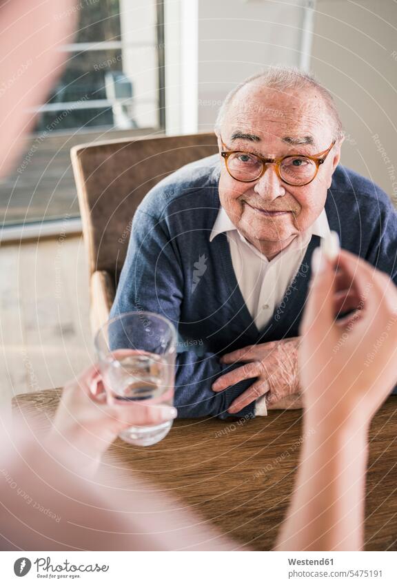 Frau hält Pille und Glas Wasser für lächelnden älteren Mann Tablette Pillen Tabletten Senior ältere Männer älterer Mann Senioren weiblich Frauen Medikament