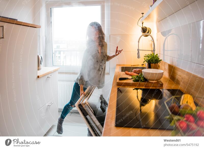 Frau öffnet dampfenden Geschirrspüler in der Küche Gesundes Essen Küchen öffnen oeffnen Geschirrspülmaschine Spülmaschine Haushalt Dampfwolke reife Frau