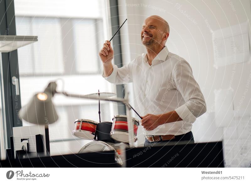 Geschäftsmann macht Lärm mit Trommeln in seinem Büro Schlagzeug Schlagzeuge Drums laut Businessmann Businessmänner Geschäftsmänner Office Büros spielen