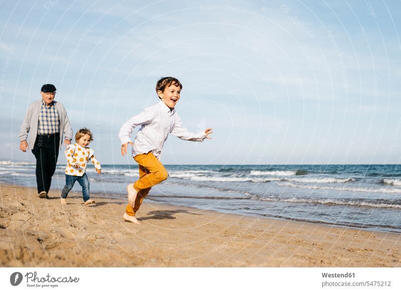 Großvater spaziert mit seinen Enkelkindern am Strand Energie dynamisch Dynamik Power Vergnügen genießen freuen Amüsement Freude vergnügt amusieren Spaß Spass