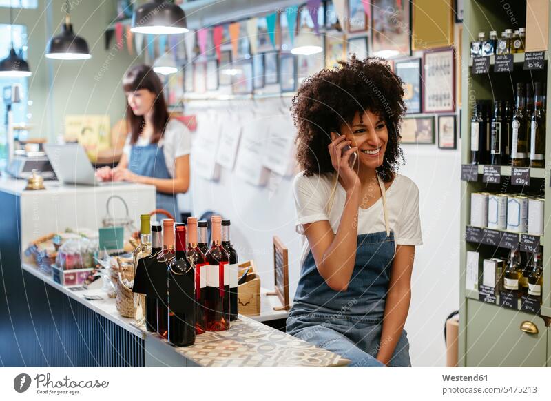 Lächelnde Frau am Telefon in einem Geschäft weiblich Frauen Handy Mobiltelefon Handies Handys Mobiltelefone Shop Laden Läden Geschäfte Shops lächeln