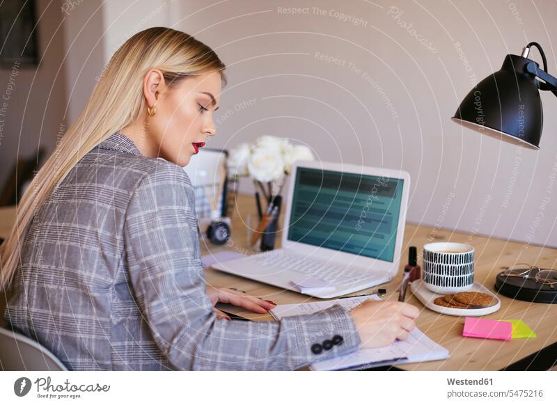 Junge Geschäftsfrau, die im Büro arbeitet und einen Laptop benutzt sitzen sitzend sitzt Geschäftsfrauen Businesswomen Businessfrauen Businesswoman blond