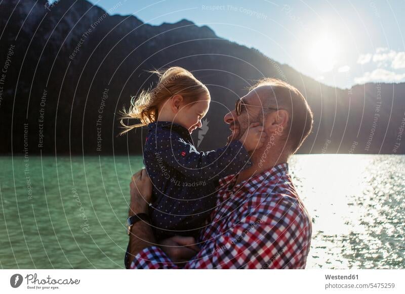 Vater trägt Tochter gegen Berg und See am Achensee, Bundesland Tirol, Österreich Farbaufnahme Farbe Farbfoto Farbphoto Außenaufnahme außen draußen im Freien Tag