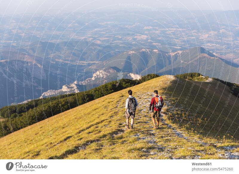 Italien, Monte Nerone, zwei Männer wandern im Sommer auf einem Berggipfel Wanderung Berge Wanderer Gipfel Mann männlich Sommerzeit sommerlich gehen gehend geht