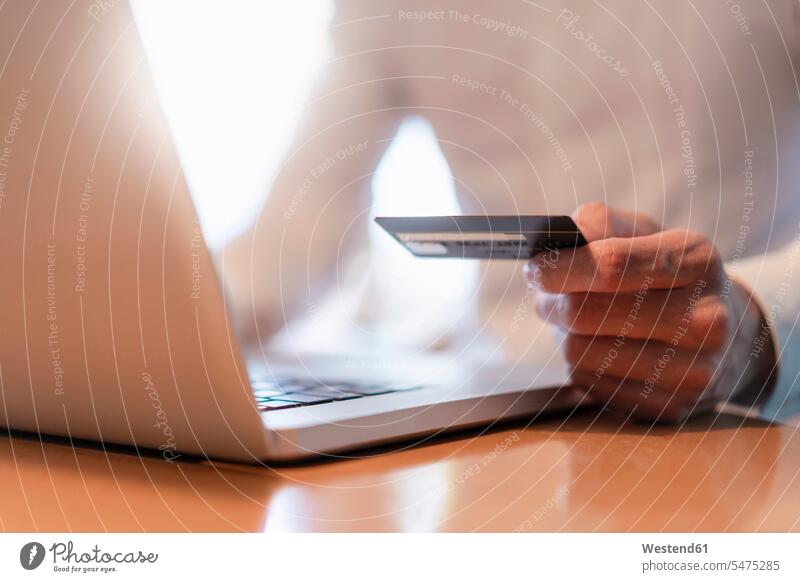 Männerhände, die eine Kreditkarte halten, während sie eine Online-Zahlung mit einem Laptop vornehmen, Nahaufnahme Geschäftsmann Businessmann Businessmänner