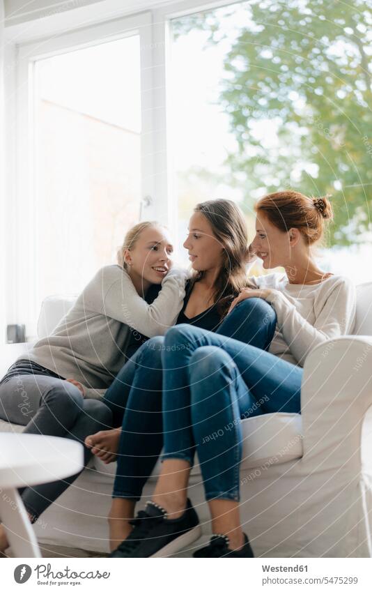 Glückliche Mutter mit zwei Teenager-Mädchen auf der Couch zu Hause glücklich glücklich sein glücklichsein Teenagerin junges Mädchen Teenagerinnen weiblich