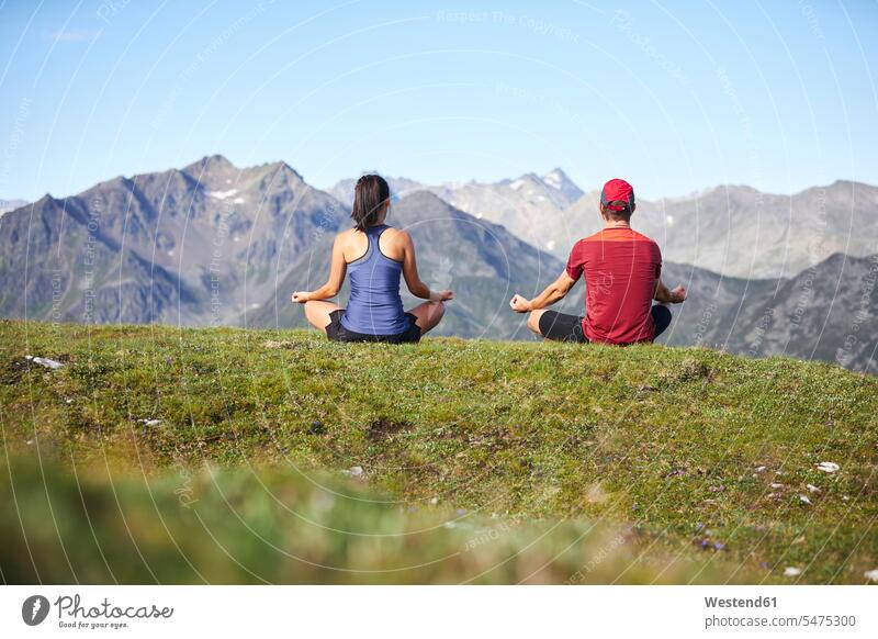Mann und Frau beim Meditieren in den Bergen, Rückansicht sitzend sitzt frei Friede friedlich Miteinander Zusammen meditieren Landschaften Berglandschaft