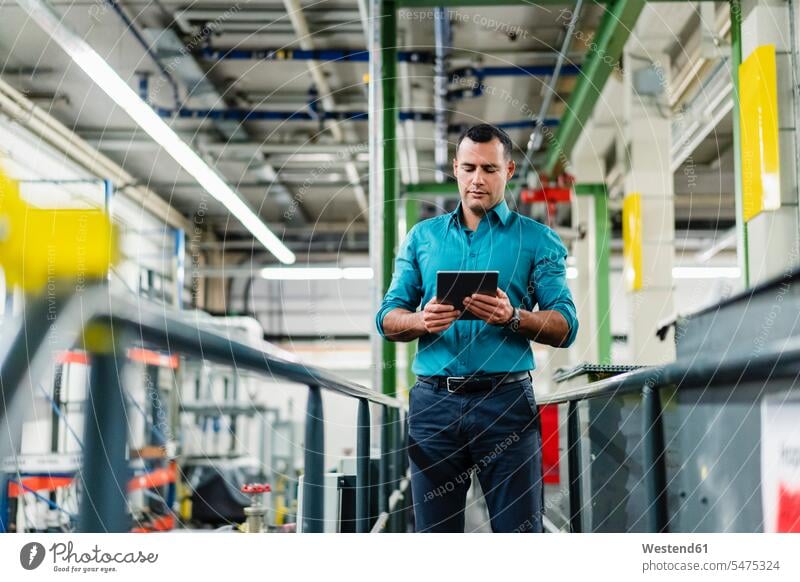 Männlicher Unternehmer, der ein digitales Tablet bei der Arbeit in der Industrie verwendet Innenaufnahme Innenaufnahmen innen drinnen Deutschland