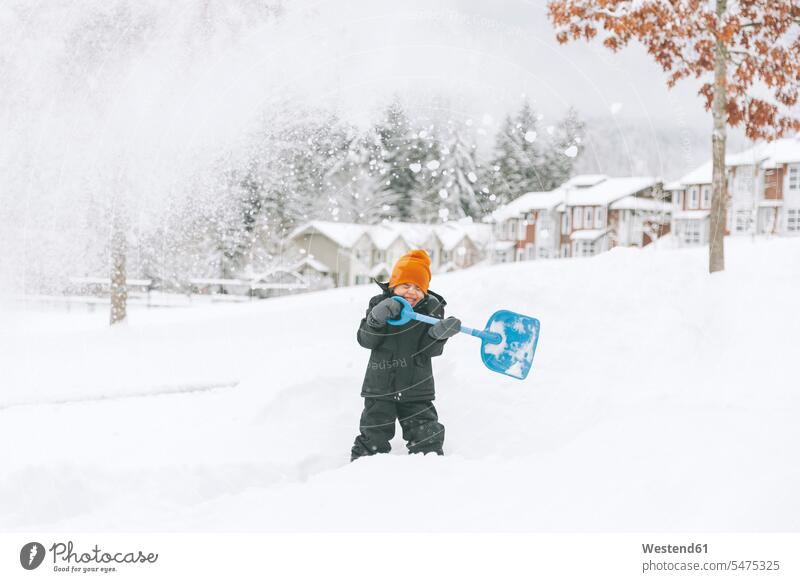 Lachender kleiner Junge schaufelt Schnee, Vancouver, Kanada Handschuhe Jahreszeiten winterlich Winterzeit freuen Frohsinn Fröhlichkeit Heiterkeit stehend steht