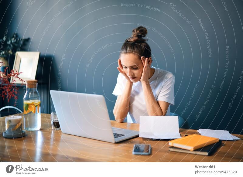 Unternehmerin mit Kopf in Händen am Schreibtisch an der Wand sitzend Farbaufnahme Farbe Farbfoto Farbphoto Freizeitkleidung Freizeitbekleidung casual