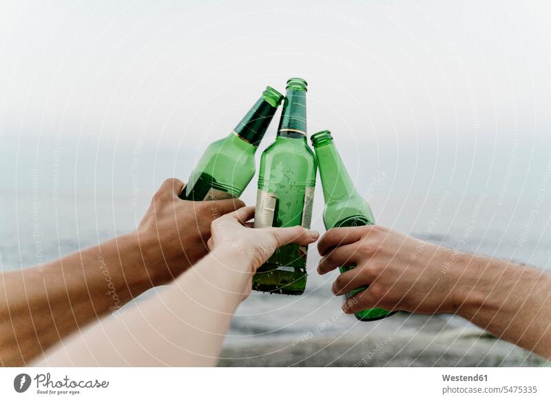 Hände dreier Freunde beim feierlichen Anstossen mit Bierflaschen Außenaufnahme außen draußen im Freien differenzierter Fokus Bulgarien Tag Tageslichtaufnahme