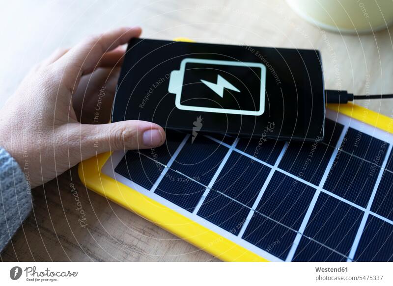 Erneuerbare Energietechnik, Solarmodul lädt einen Handy-Akku aufladen Symbolbild Symbolik Smartphone iPhone Smartphones Hände Sonnenenergie Solarenergie