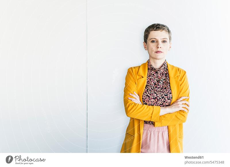 Selbstbewusste Geschäftsfrau in gelbem Blazer steht im Büro an weißer Wand Farbaufnahme Farbe Farbfoto Farbphoto Deutschland Innenaufnahme Innenaufnahmen innen