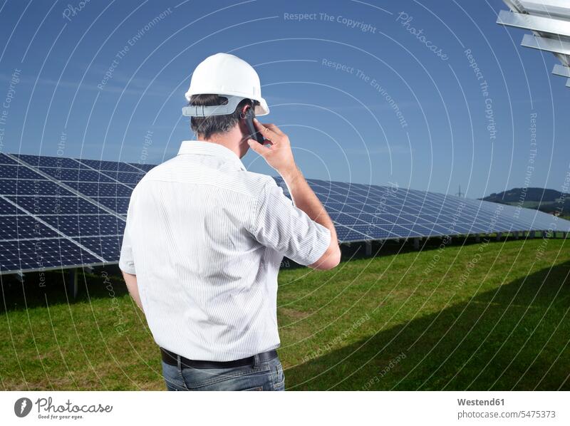 Rückansicht des Ingenieurs am Telefon vor der Solaranlage Sonnenkraftwerke Sonnenwärmekraftwerke Solarkraftwerke Solaranlagen Ingenieure telefonieren anrufen