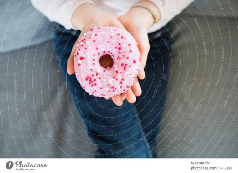 Mädchenhand hält rosa Doughnut, Nahaufnahme Hand Hände weiblich Donut Donuts Doughnuts halten Mensch Menschen Leute People Personen Kind Kinder Kids Gebäck