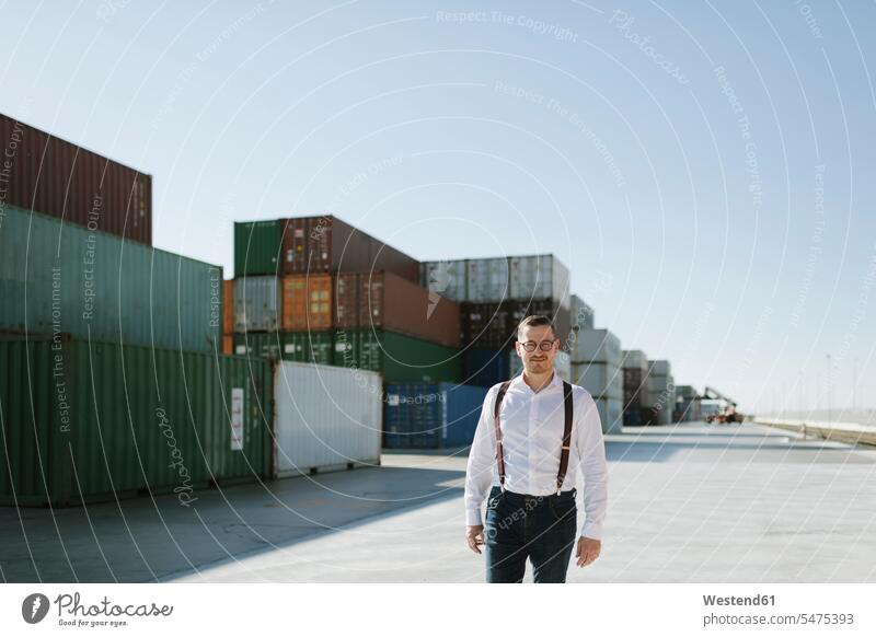 Manager vor Frachtcontainern auf einem Industriegelände Spanien Export exportieren Import Warenumschlag Logistikunternehmen Zuversicht Zuversichtlich