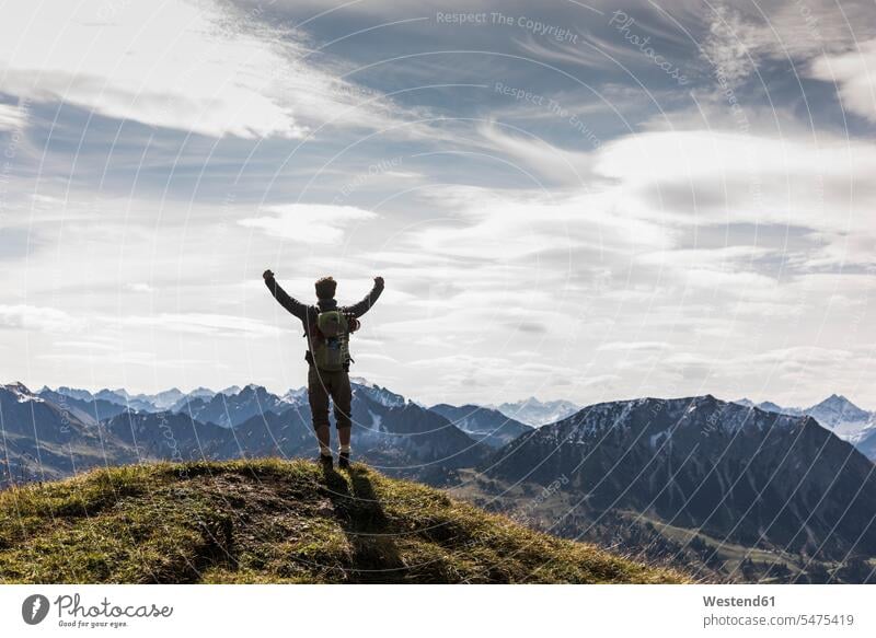 Österreich, Tirol, junger Mann steht jubelnd in Berglandschaft Gebirge Gebirgslandschaft Gebirgskette Gebirgszug Berge Jubel stehen stehend wandern Wanderung