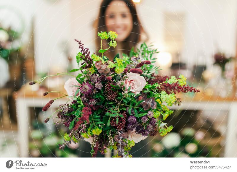 Frau hält Blumenstrauss, während sie im Blumenladen steht Farbaufnahme Farbe Farbfoto Farbphoto Innenaufnahme Innenaufnahmen innen drinnen stehen stehend
