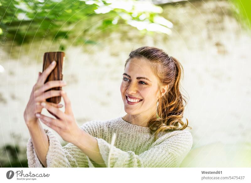 Porträt einer entspannten Frau, die ein Selfie mit ihrem Mobiltelefon macht Selfies Portrait Porträts Portraits Smartphone iPhone Smartphones weiblich Frauen