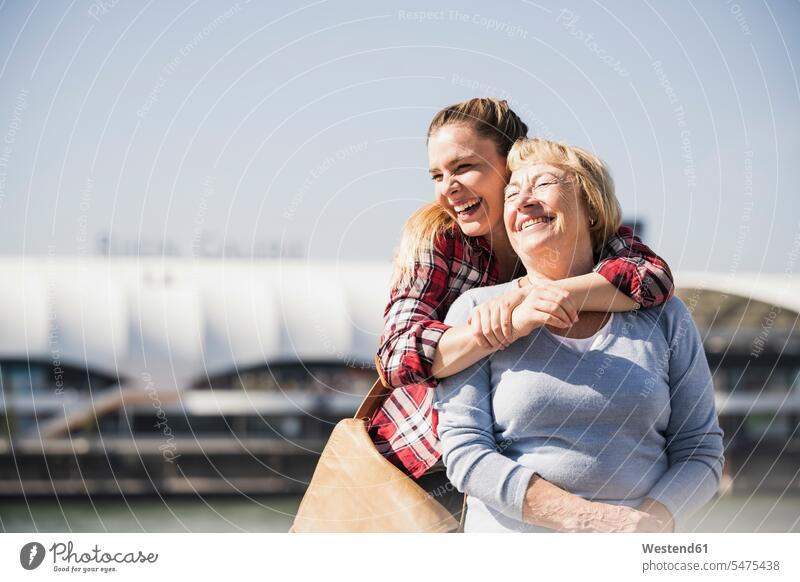 Junge Frau umarmt ihre lächelnde Großmutter, die im Rollstuhl sitzt Generation entspannen relaxen Arm umlegen Umarmung Umarmungen freuen geniessen Genuss Glück