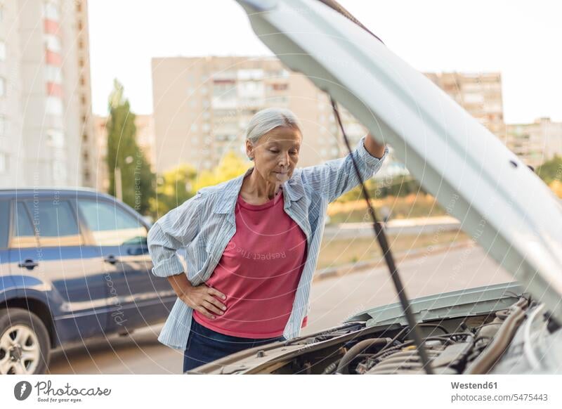 Ältere Frau schaut auf Automotor ansehen weiblich Frauen Seniorin älter Seniorinnen alt Motor Motoren schauen sehend Erwachsener erwachsen Mensch Menschen Leute