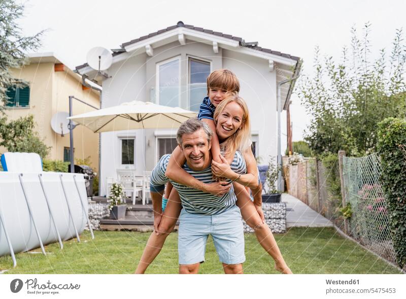 Porträt eines Vaters, der Frau und Sohn huckepack im Garten trägt sommerlich Sommerzeit begeistert Enthusiasmus enthusiastisch Überschwang Überschwenglichkeit