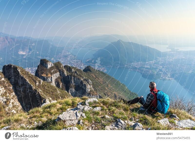 Rückansicht eines auf dem Berggipfel sitzenden Wanderers, Orobie Alps, Lecco, Italien Leute Menschen People Person Personen Europäisch Kaukasier kaukasisch 1