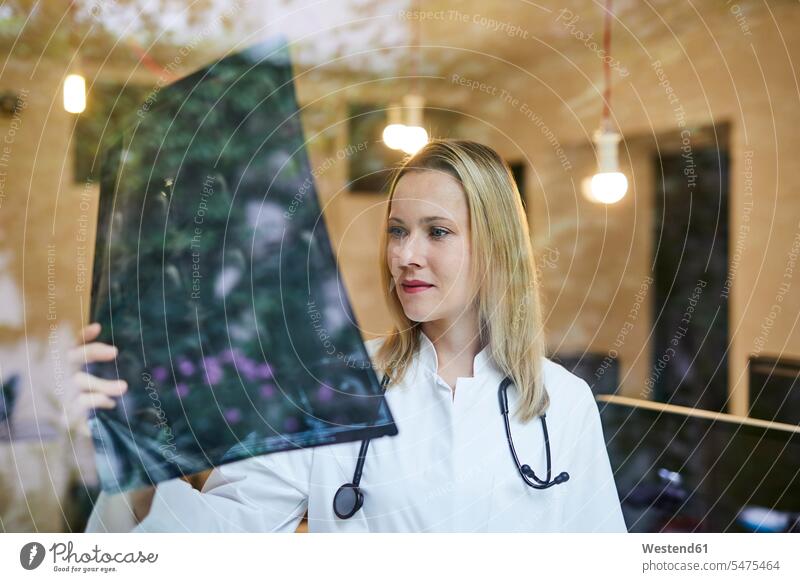 Ärztin schaut auf Röntgenbild hinter Fensterscheibe Roentgenbild Roentgenbilder Röntgenbilder Frau weiblich Frauen ansehen Fensterscheiben Aerztin Ärztinnen