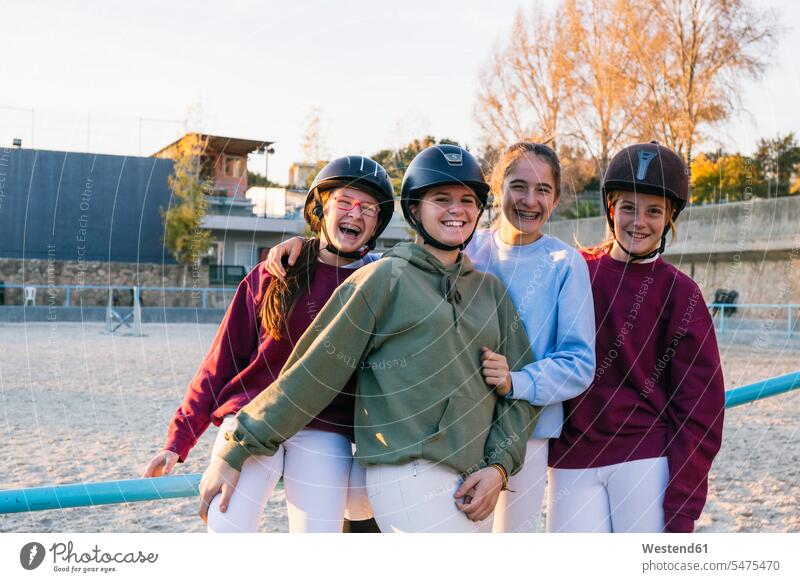 Porträt fröhlicher weiblicher Jockeys, die zusammen auf dem Übungsplatz gegen den Himmel stehen Farbaufnahme Farbe Farbfoto Farbphoto Rennreiter Reitsport