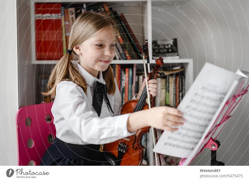Lächelndes Mädchen mit Geige schaut auf Noten auf dem Notenständer Violine Geigen Violinen Notenpult Notenstaender Notenpulte Zuversicht Zuversichtlich